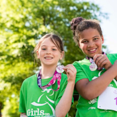 Two Girls on the Run participants smile while showing off 5K medals